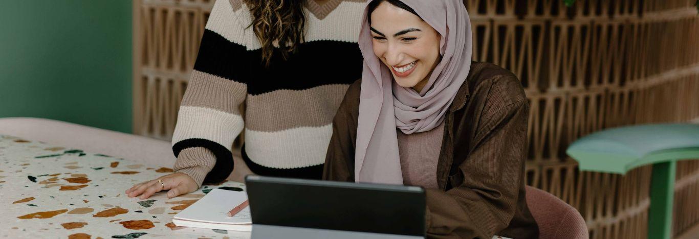 mulher mostrando para outra pessoa ao lado o site do teste grátis da pós-graduação descomplica