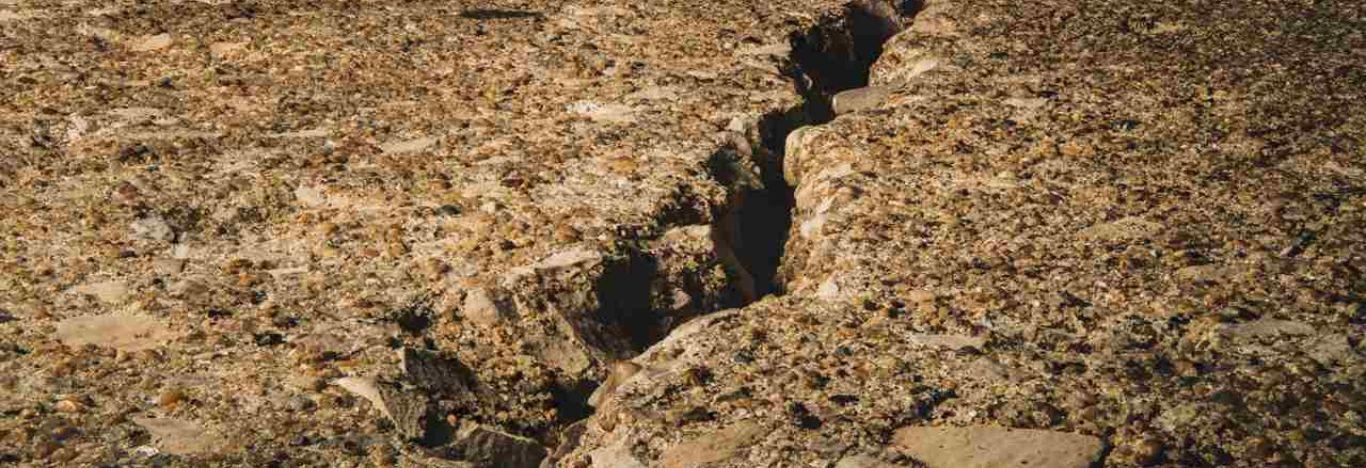 Imagem de uma rachadura no chão, consequência de um terremoto.