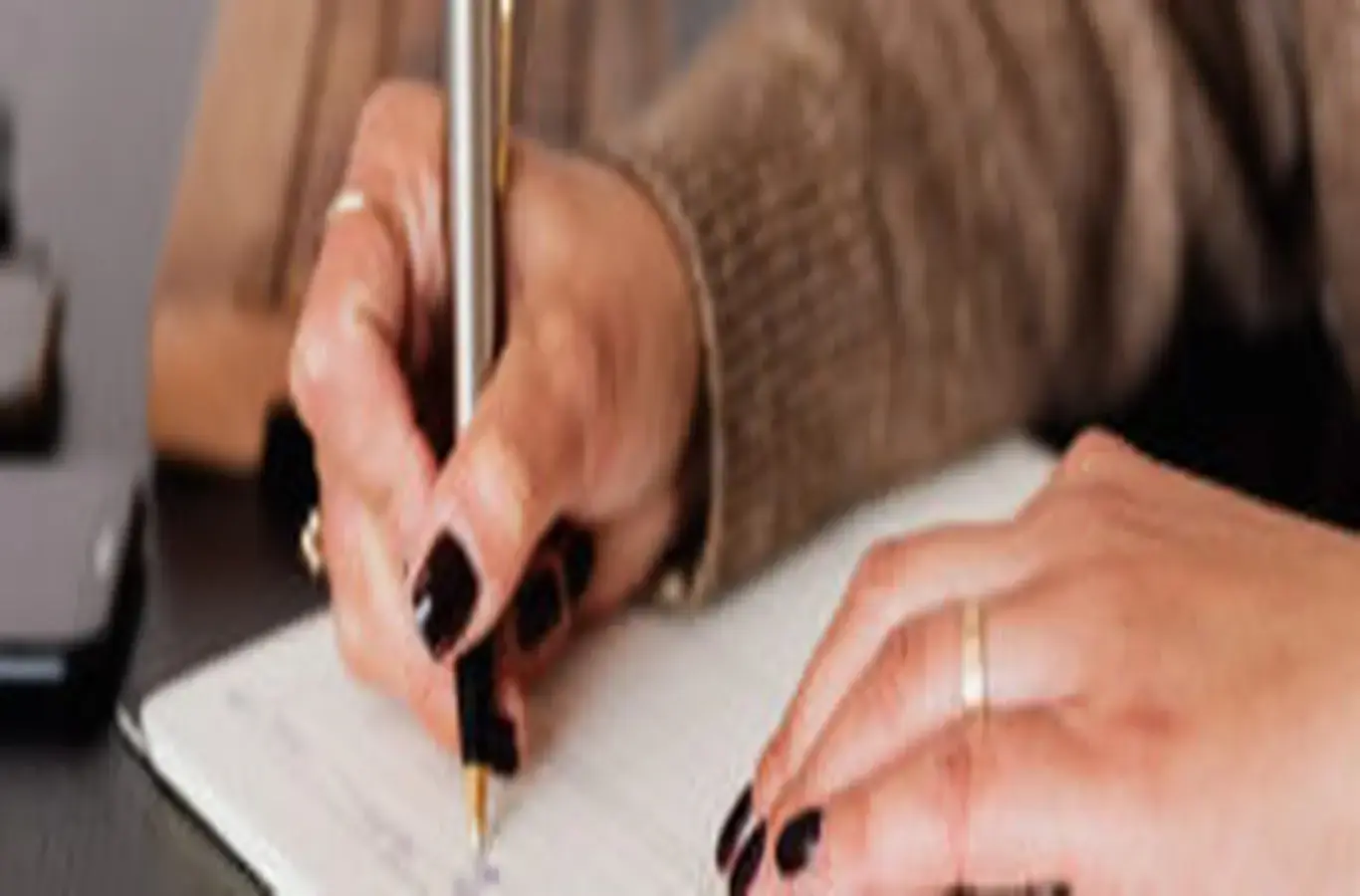 mão de mulher escrevendo em caderno para ilustrar texto sobre questões de coesão textual