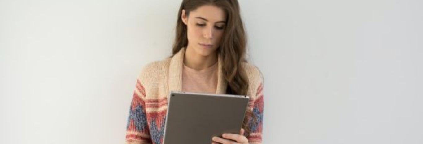 mulher lendo um conteúdo sobre eixo temático e questões sociais em um tablet