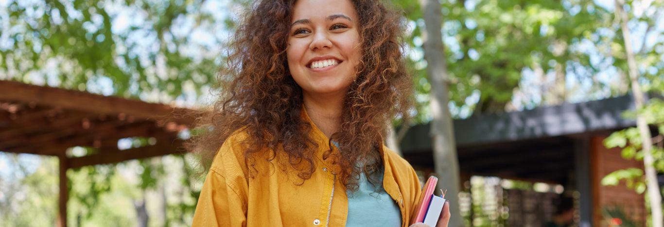 pessoa segurando livros e sorrindo pensando no aditamento do fies