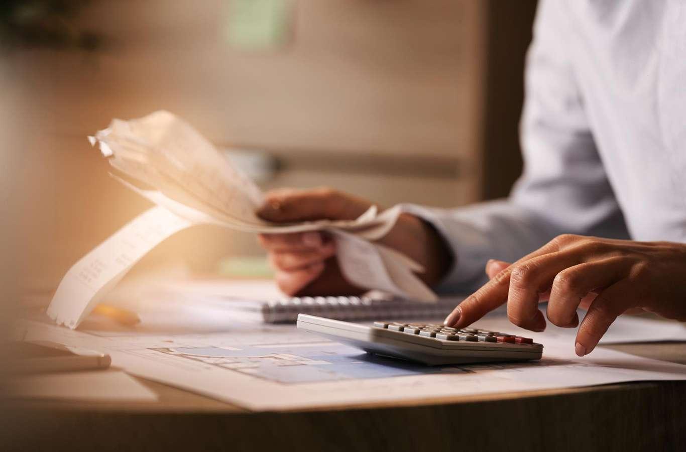 Homem com um papel na mão fazendo cálculo para ilustrar o texto sobre como escolher a faculdade de contabilidade