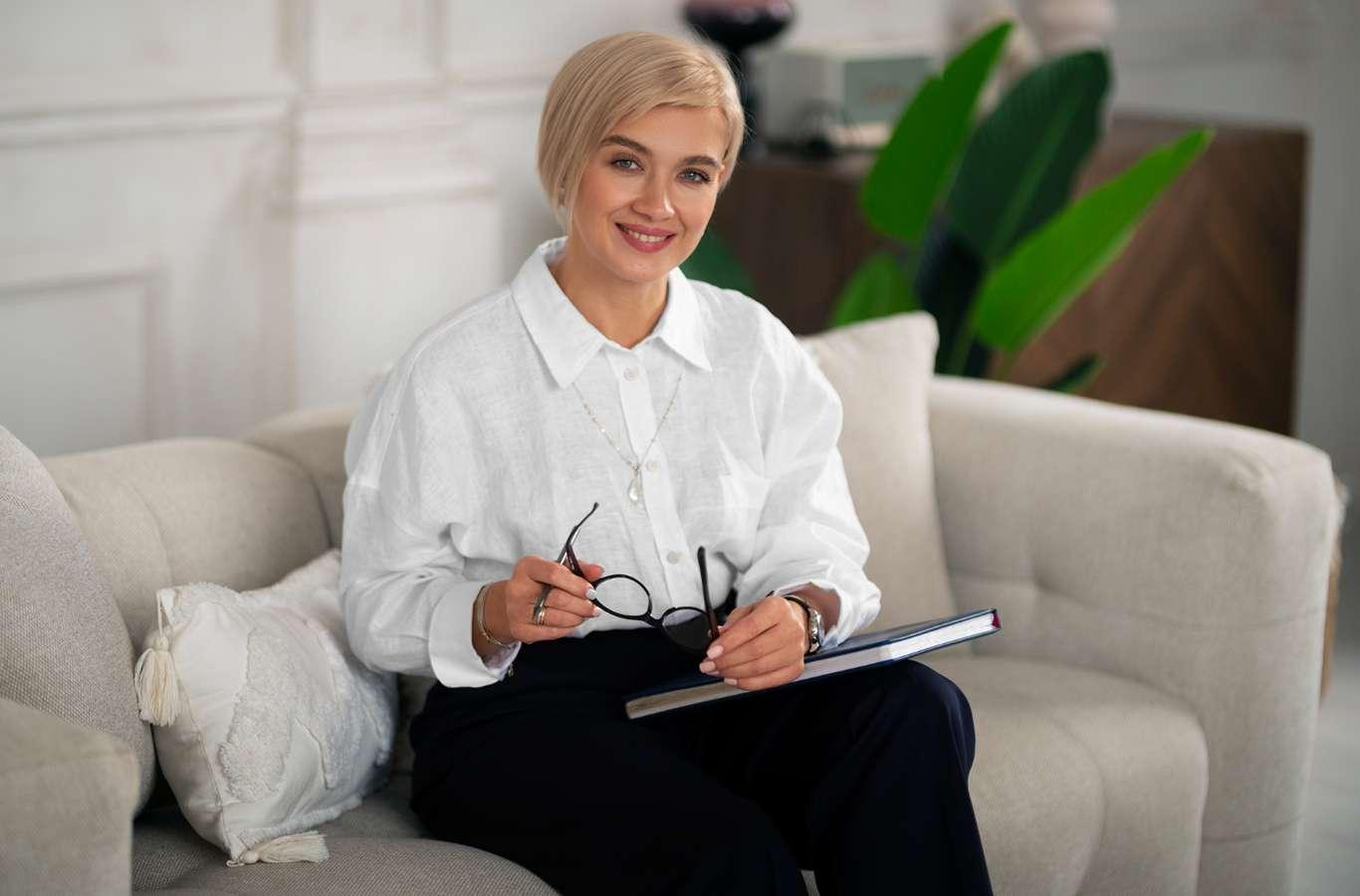 Psicóloga sentada em um sofá com um livro na mão para ilustrar o texto sobre o que psicologia forense