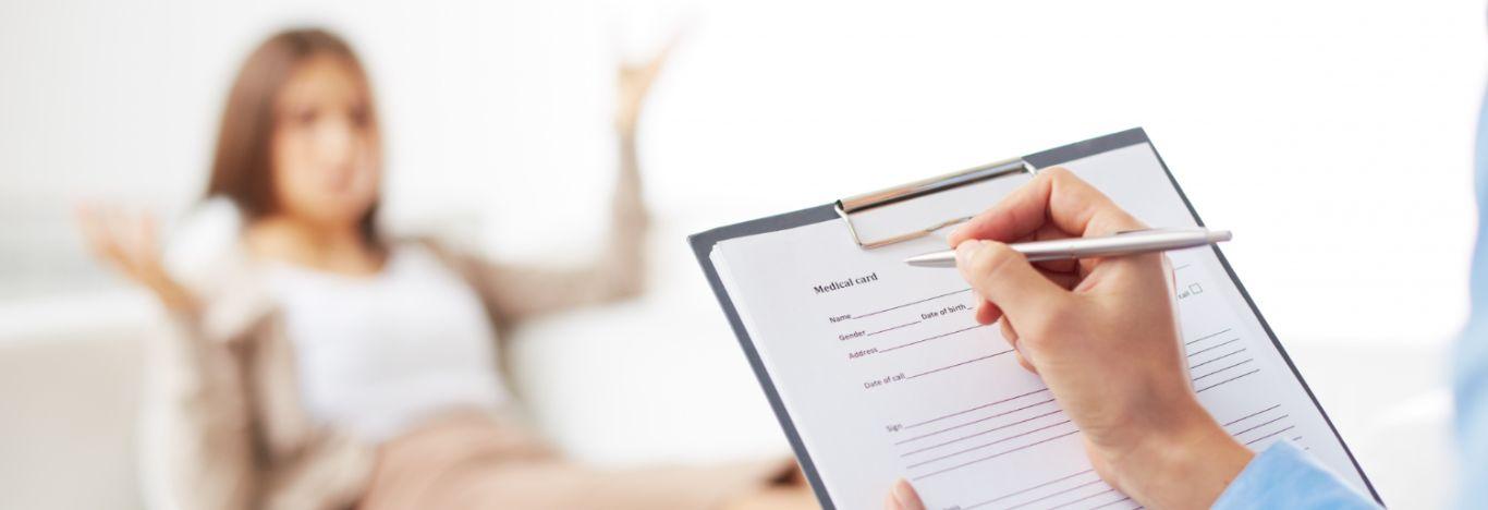 pessoa sentada em e outra pessoa segurando um papel anotando informações para ilustrar o conteúdo sobre pós-graduação em psicologia