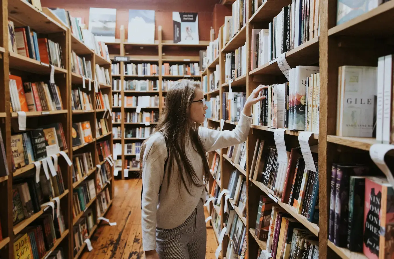 menina procurando livros da fuvest 2023 em uma biblioteca