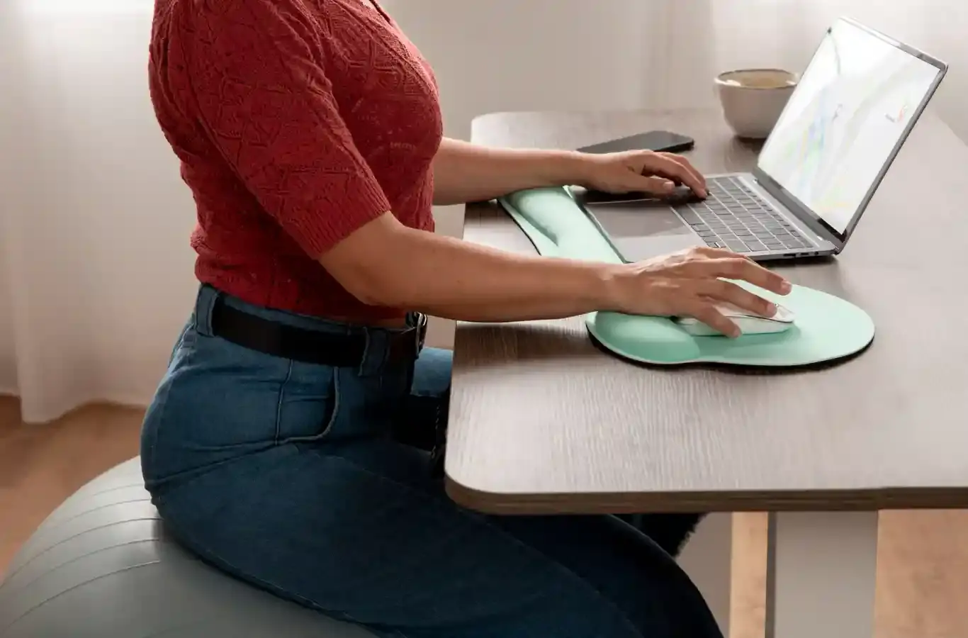 Jovem sentada trabalhando no notebook para ilustrar texto sobre ergonomista