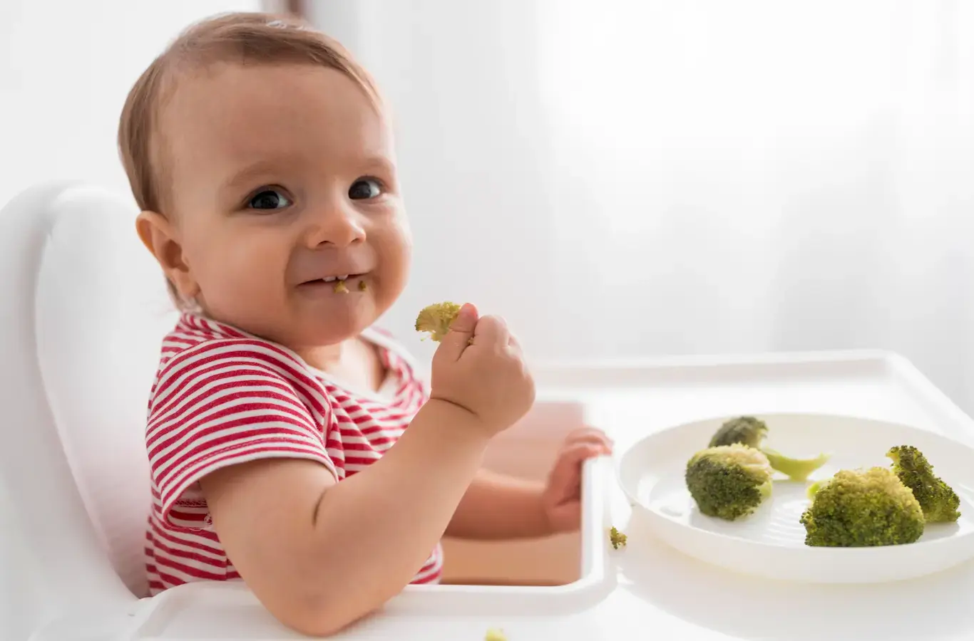 Bebê comendo brócolis para ilustrar conteúdo sobre nutricionista materno infantil