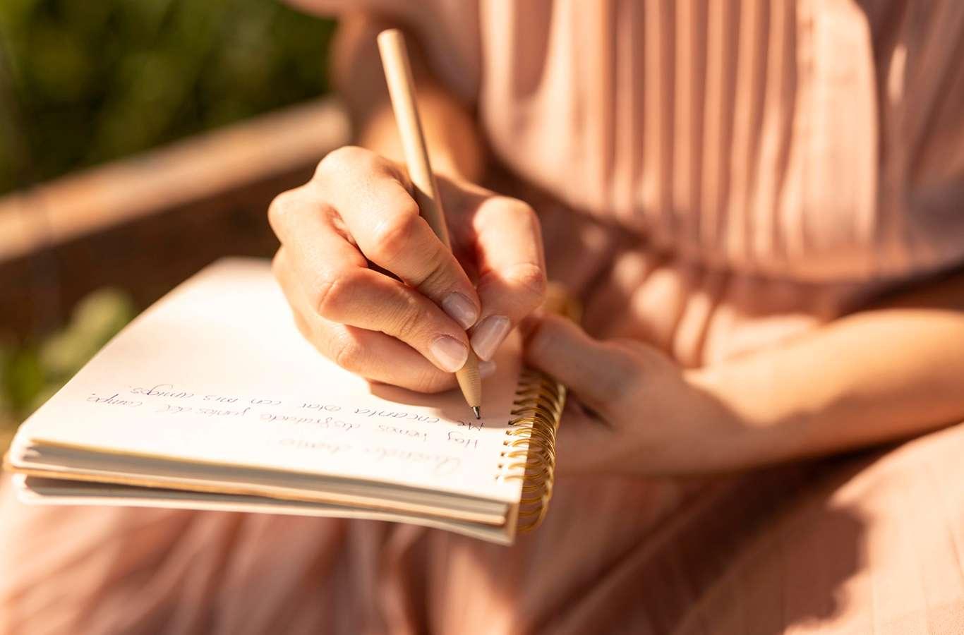 Mulher escrevendo em um caderno para ilustrar o texto conclusão de  redação Enem