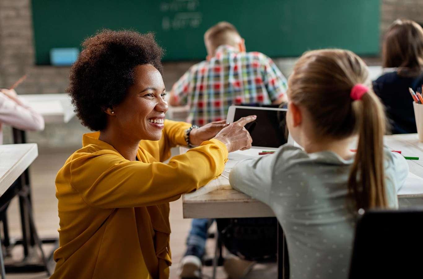 A imagem mostra uma mulher negra conversando com um aluno para ilustrar o texto sobre projeto pedagógico