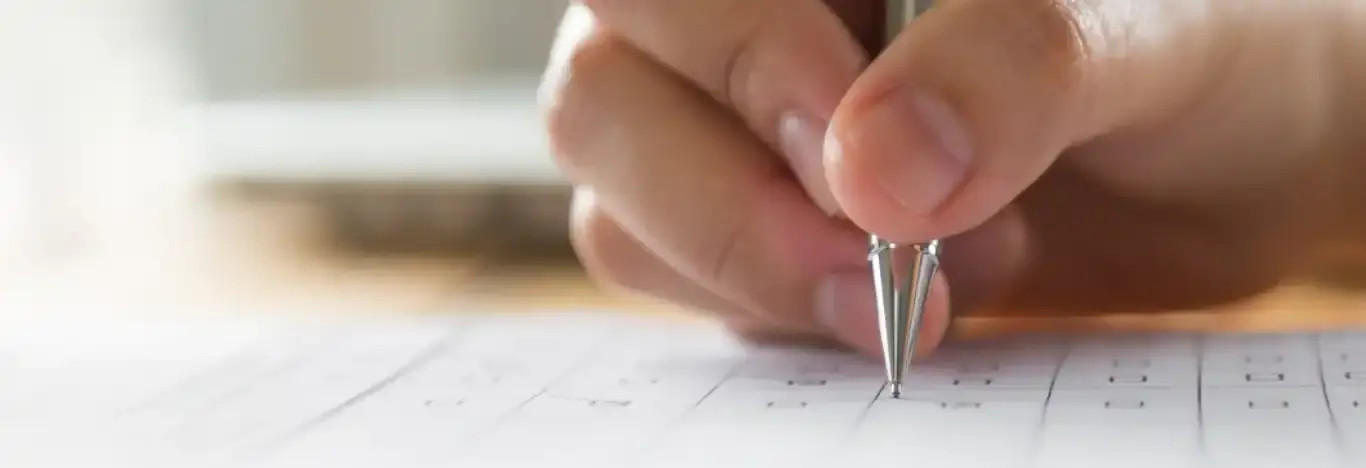 Imagem de uma mão segurando uma caneta escrevendo em um cartão resposta de prova para ilustrar artigo sobre assuntos que mais caem no enem