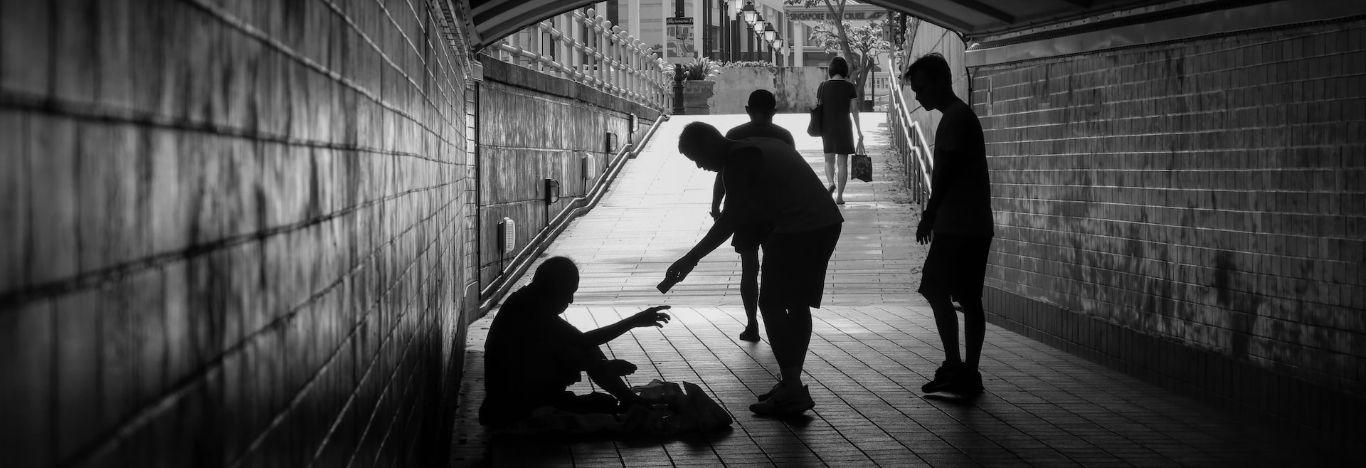 pessoa oferecendo ajuda a uma pessoa em situação de rua para ilustrar o conteúdo sobre problemas sociais no Brasil e no mundo