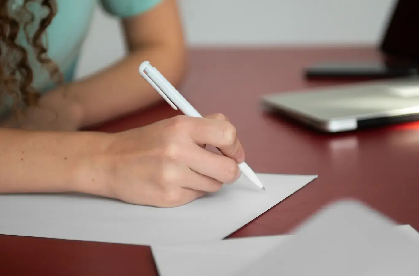 Redação nota 1000 sendo representada por uma pessoa iniciando uma redação em um papel com um lápis.