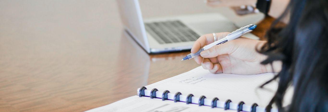 pessoa escrevendo em um caderno as estruturas dos tempos verbais em inglês