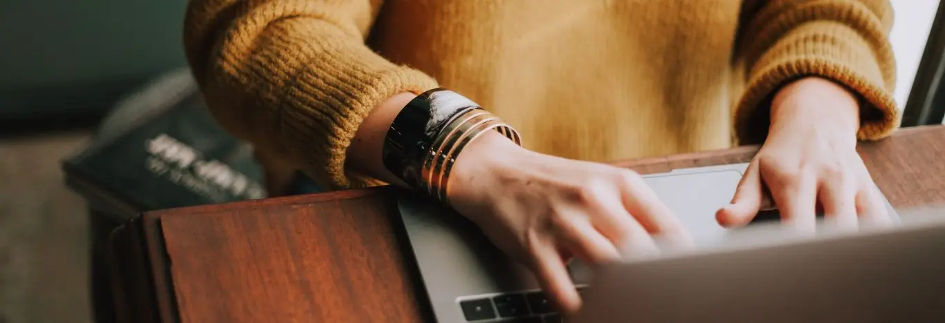 pessoa usando pulseiras no braço pesquisando em um notebook que está em cima de uma mesa o que é analogia