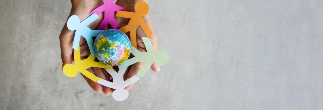 Recortes de bonecos simulando pessoas de mãos dadas ao redor do planeta terra, ilustrando o que é sociologia e qual o seu papel na sociedade.