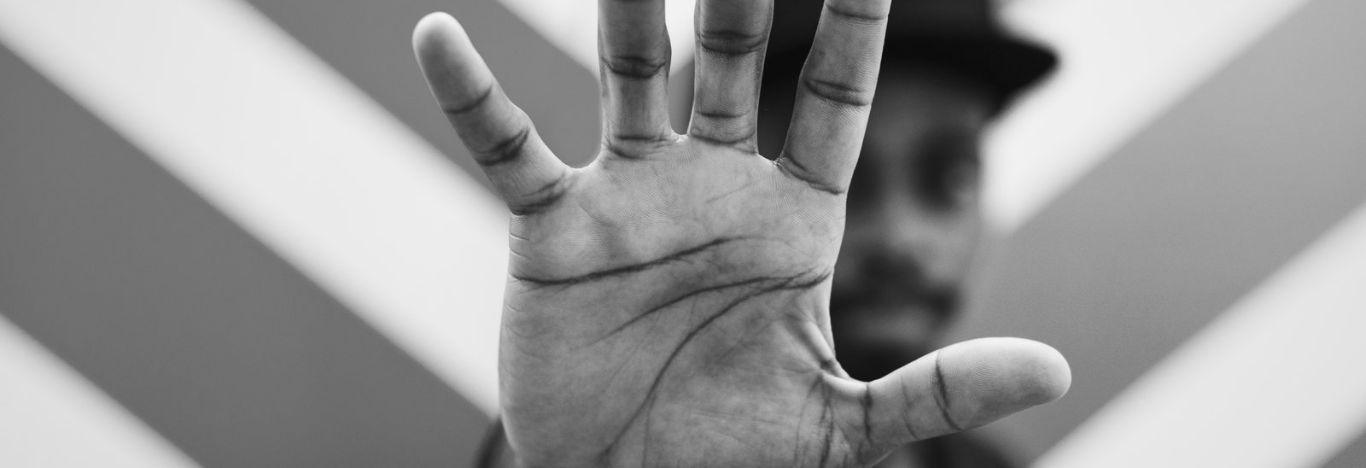 Intolerância religiosa no brasil ilustrada na imagem com um rapaz em pose de "dar um basta" olhando para a câmera.