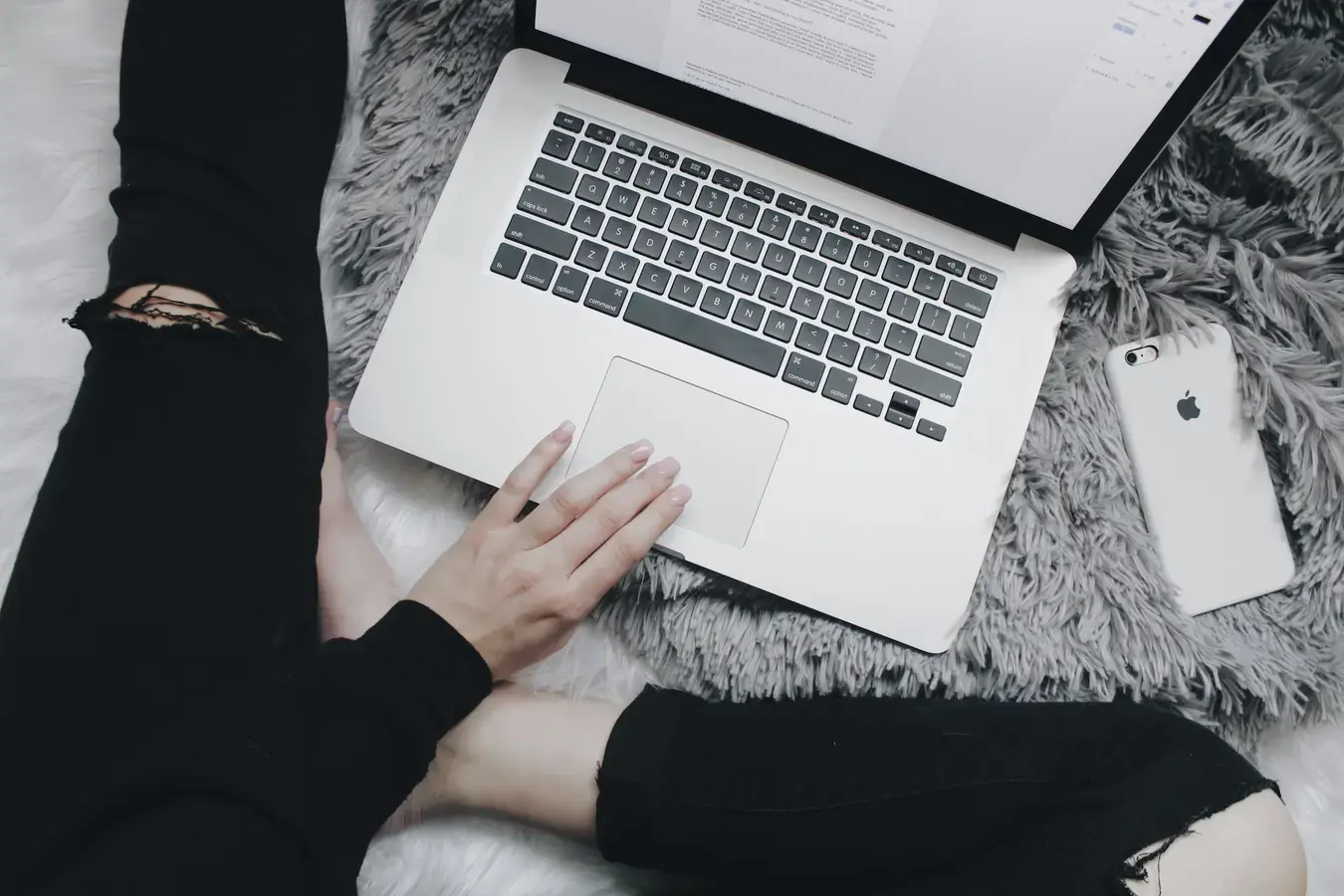 pessoa sentada no chão com uma mão apoiada no notebook que está na frente pesquisando sobre enem resultado
